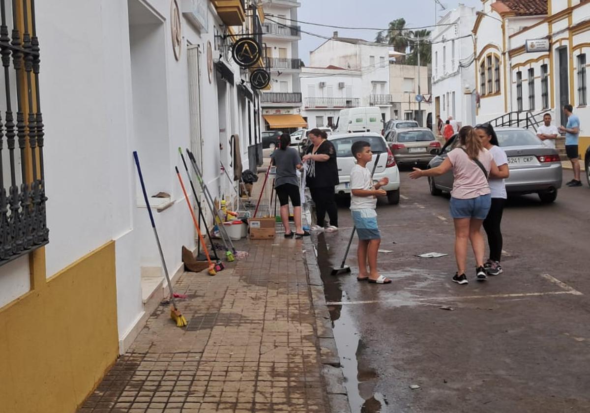 Los vecinos han sacado cepillos y cubos para limpiar los restos de la tormenta de agua y granizo en Los Santos de Maimona.