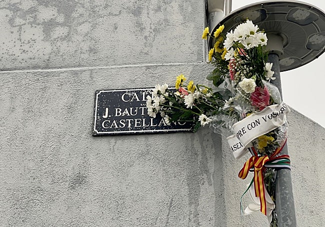 Ramo de flores junto a la placa de la calle dedicada a la víctima del terrorismo, en Abadía.