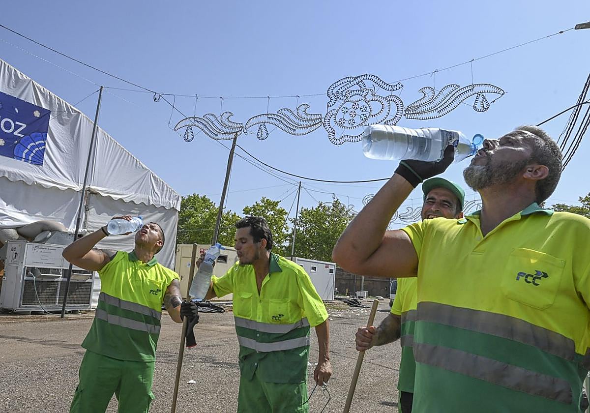 Trabajadores de limpieza se hidratan este domingo en el recinto ferial de Badajoz.