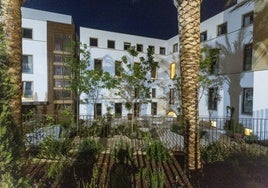 Fachada del Hotel Palacio de Godoy vista desde la calle Zapatería con algunas de sus estancias iluminadas y el jardín rematado.
