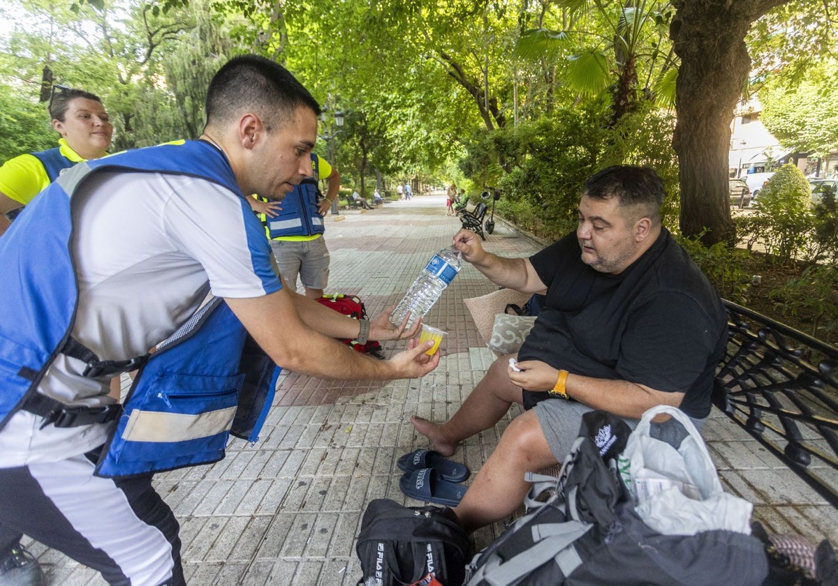 Los voluntarios de DYA Social entregan un kit de hidratación a Jacobo, de 50 años, este miércoles en el Paseo de Cánovas.