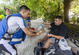 Los voluntarios de DYA Social entregan un kit de hidratación a Jacobo, de 50 años, este miércoles en el Paseo de Cánovas.