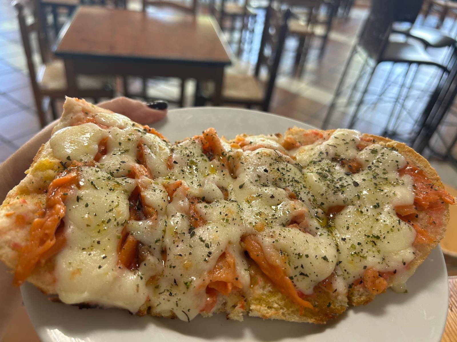 En un pan de mollete con una base de tomate natural triturado con Aove, le añaden salmón ahumado a taquitos y lo cubren con una abundante capa de mozzarella y un toque de orégano que pasan a fundir en la tostadora.