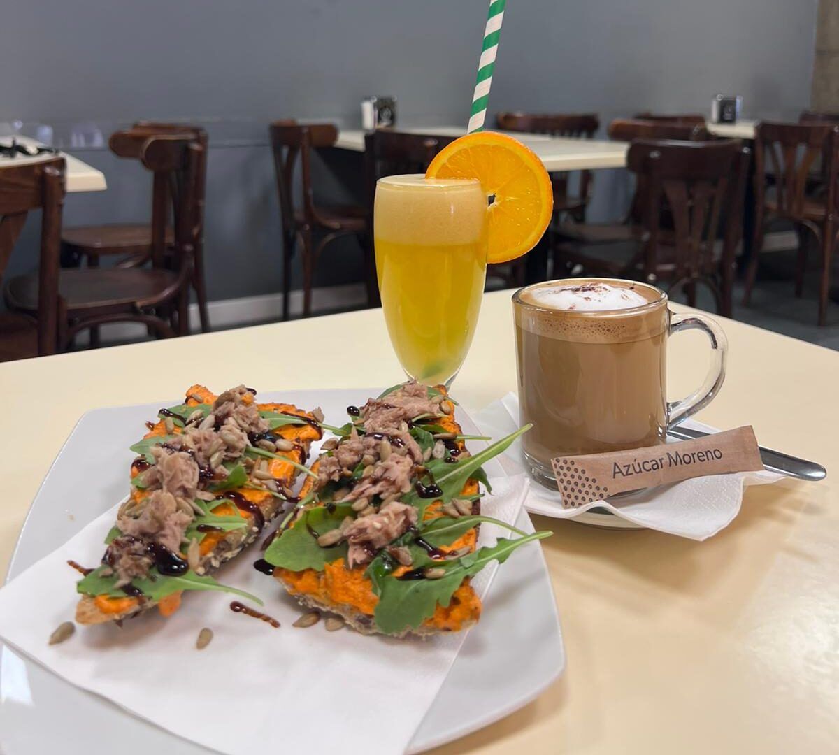 Café + Zumo tropical + tostada en pan de semillas con crema de pimiento del piquillo, bonito del norte, rúcula y AOVE.