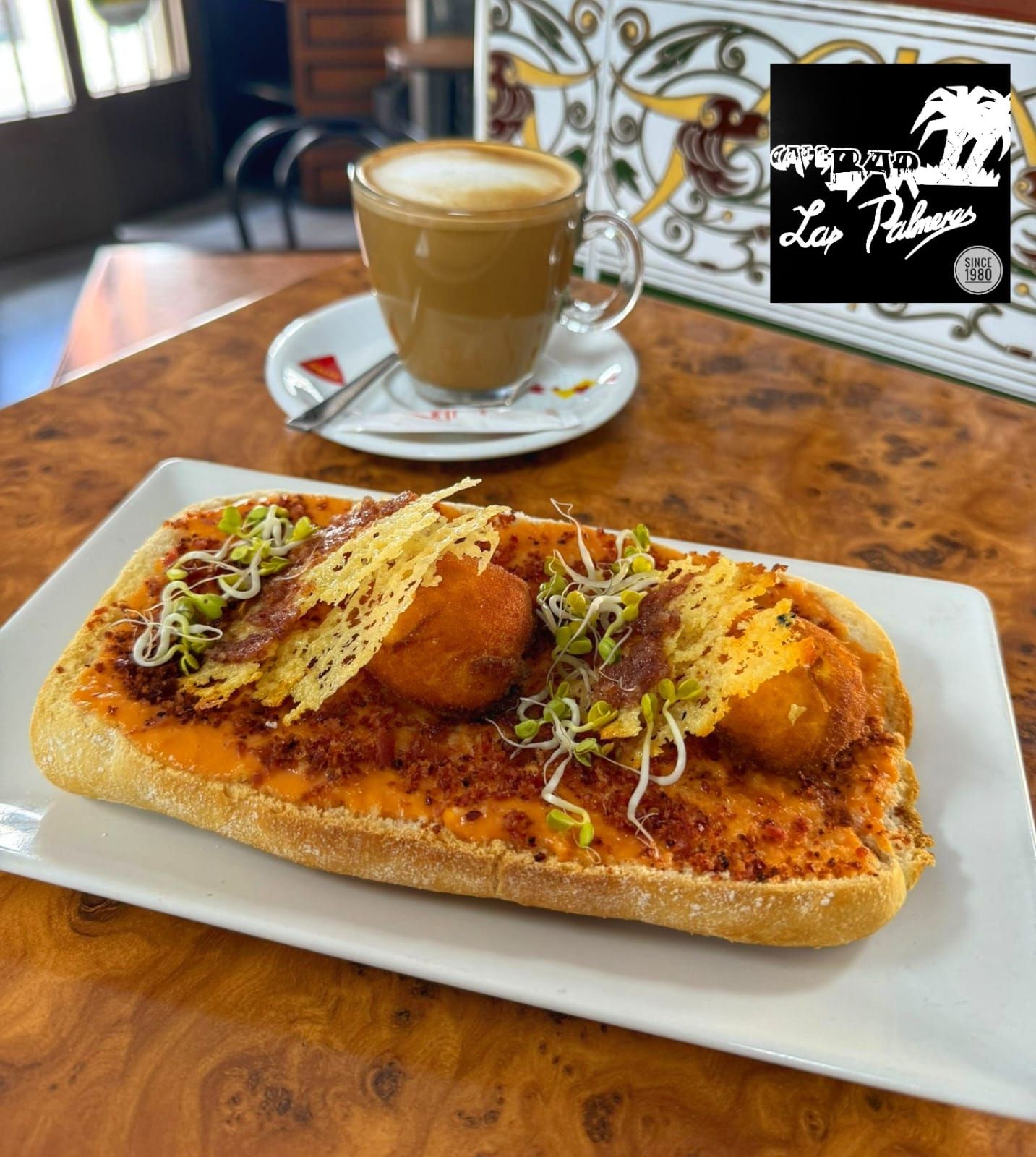 Tostada de pan artesano con base de salmorejo casero, polvo de bacon deshidratado, dos yemas fritas, chips de queso portugués con mermelada de jamón casera y brotes germinados