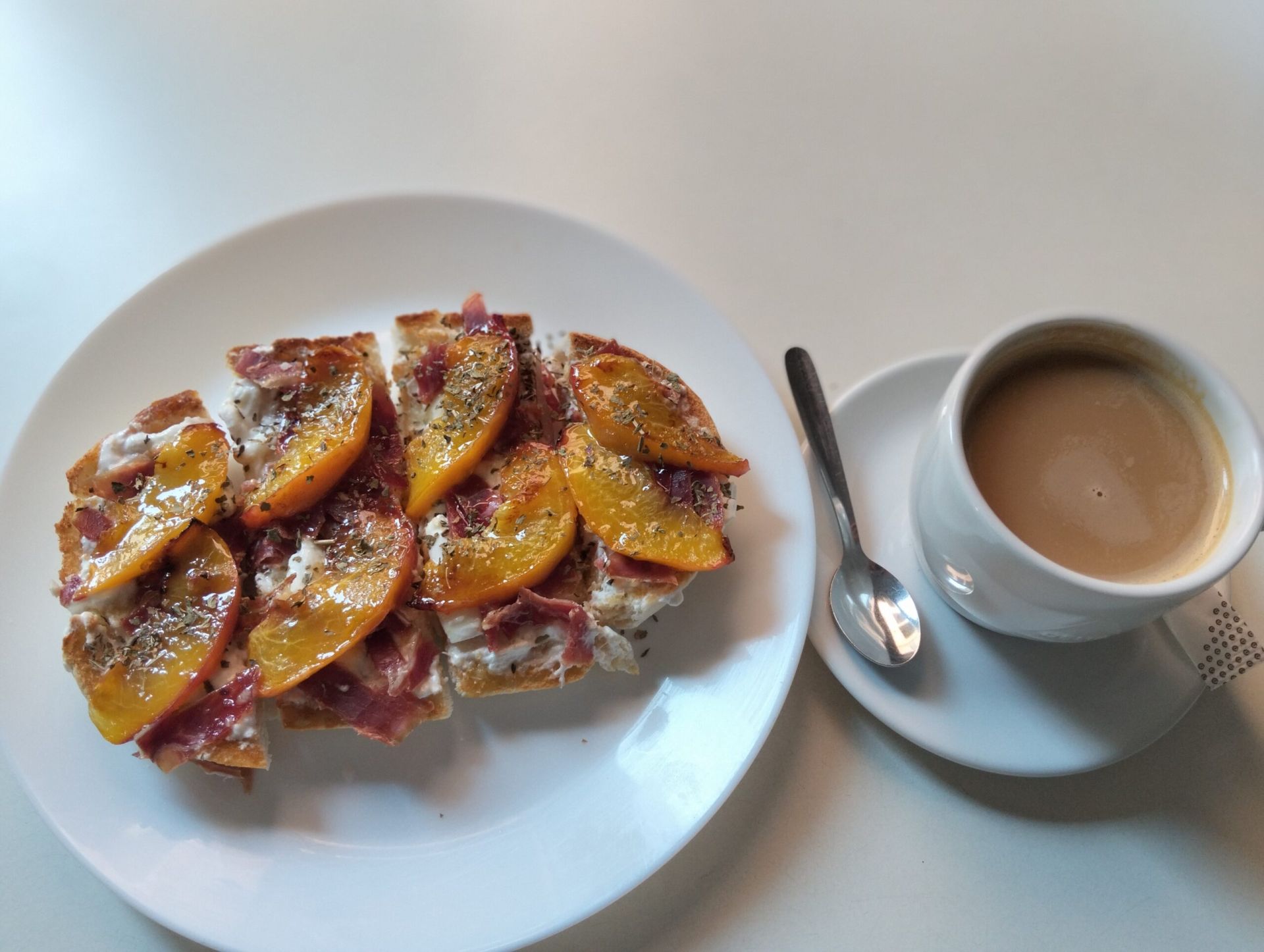 Un desayuno fresco, con base de mantequilla con ajo, queso burrata, albahaca, jamón ibérico, nectarina y miel. Es una tostada para desgustarla templada.