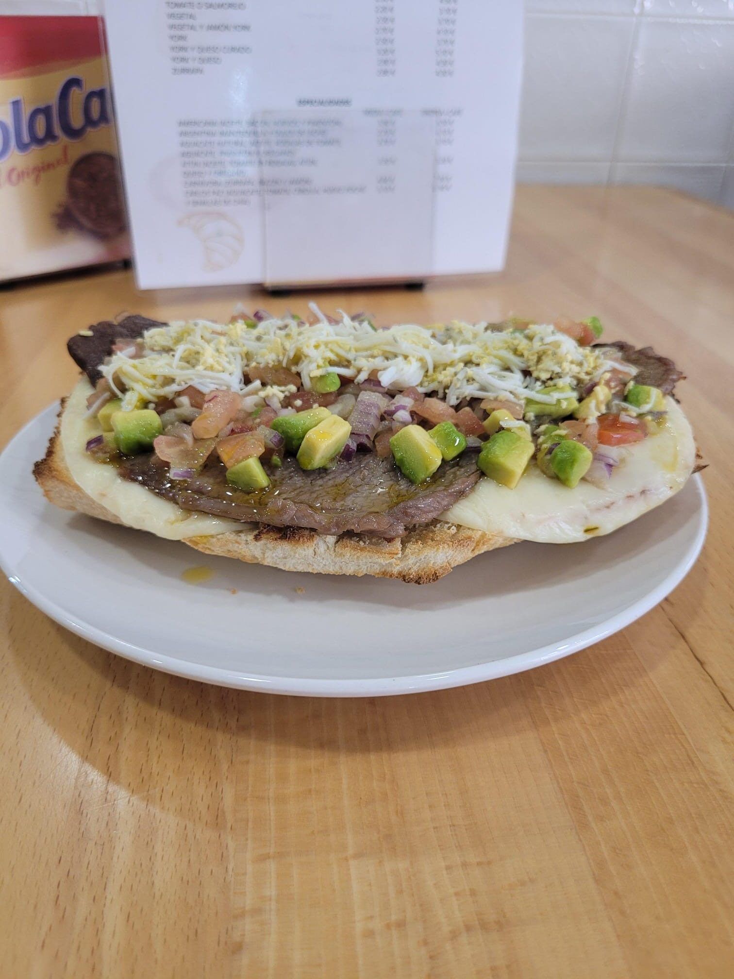 Pan de mollete blanco con base cremosa, ternera a la brasa con un toque de salsa argentina de aguacate