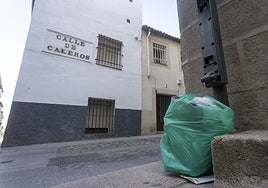 Una bolsa de basura depositada en el hueco de una papelera junto a la calle Caleros.