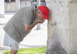 Un hombre se refresca del sofocante calor en una fuente.