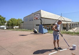 Dos operarios pintan las pistas deportivas del colegio Pastor Sito.
