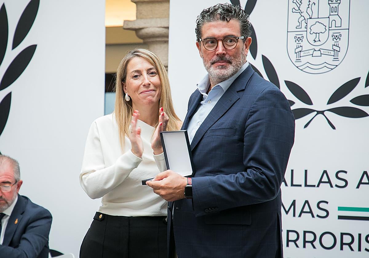 La presidenta de la Junta de Extremadura, María Guardiola, entrega una medalla al director de ABC, Julián Quirós.