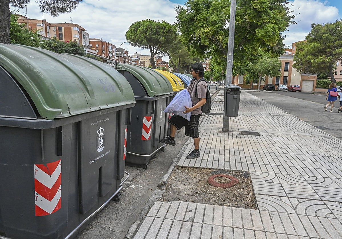 Un pacense deposita una bolsa de basura a un contenedor en Valdepasillas.
