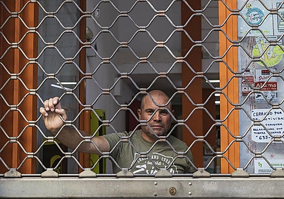 Juan Francisco bajando las persianas de su local en Badajoz.