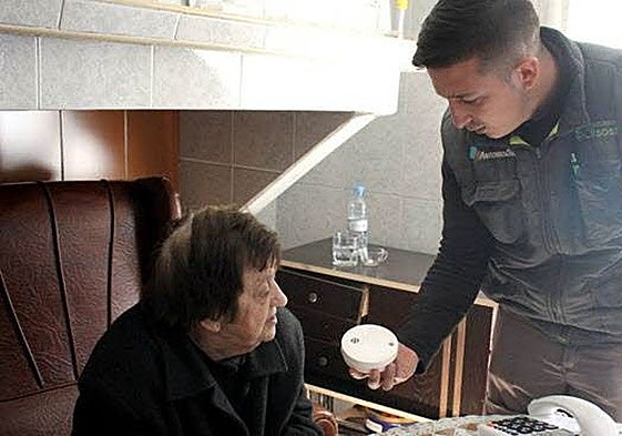 Un técnico explica a una mujer el uso de un detector de incendios en una imagen de archivo.