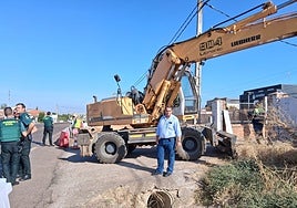 El propietario junto a su vivienda de la carretera de Sevilla mientras los operarios derriban el cerramiento este martes.