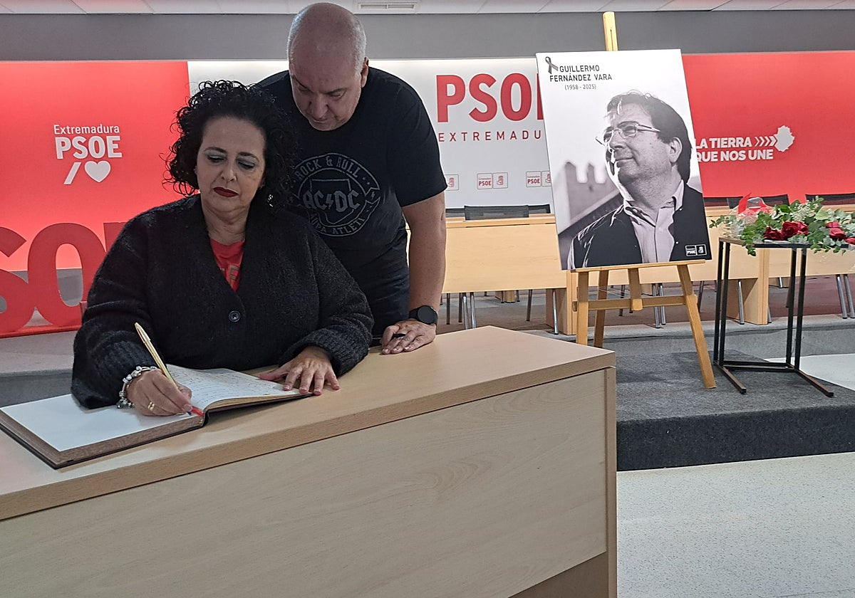 Mercedes Custodio y su marido, Francisco Javier Carreras, firman esta mañana en el libro de condolencias habilitado por el PSOE extremeño en su sede regional, en Mérida.
