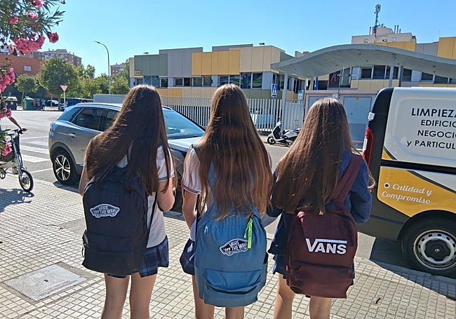 Tres adolescentes con sus mochilas a la salida del centro escolar.
