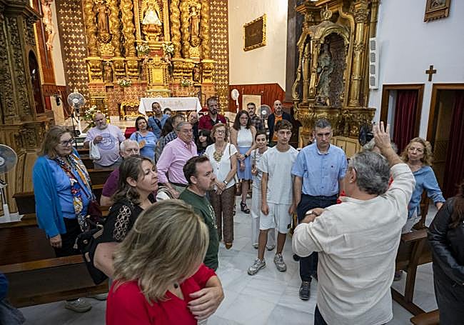 Explicaciones en la iglesia, con el retablo barroco de fondo.