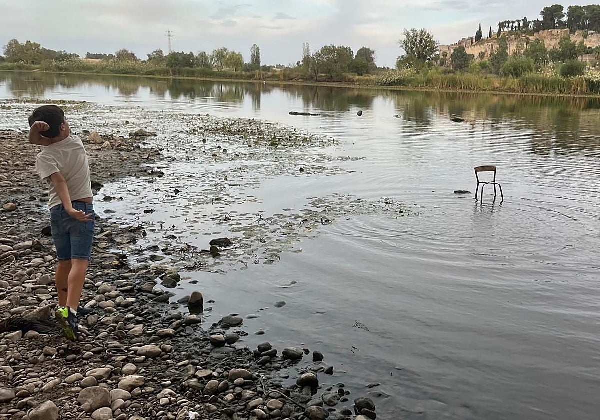 Un niño pasea por el lecho del río y lanza piedras aprovechando la bajada del nivel del agua.