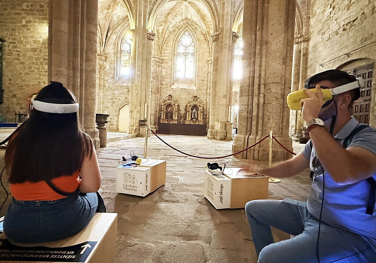 Dos turistas utilizan unas gafas de realidad virtual en la catedral de Plasencia.