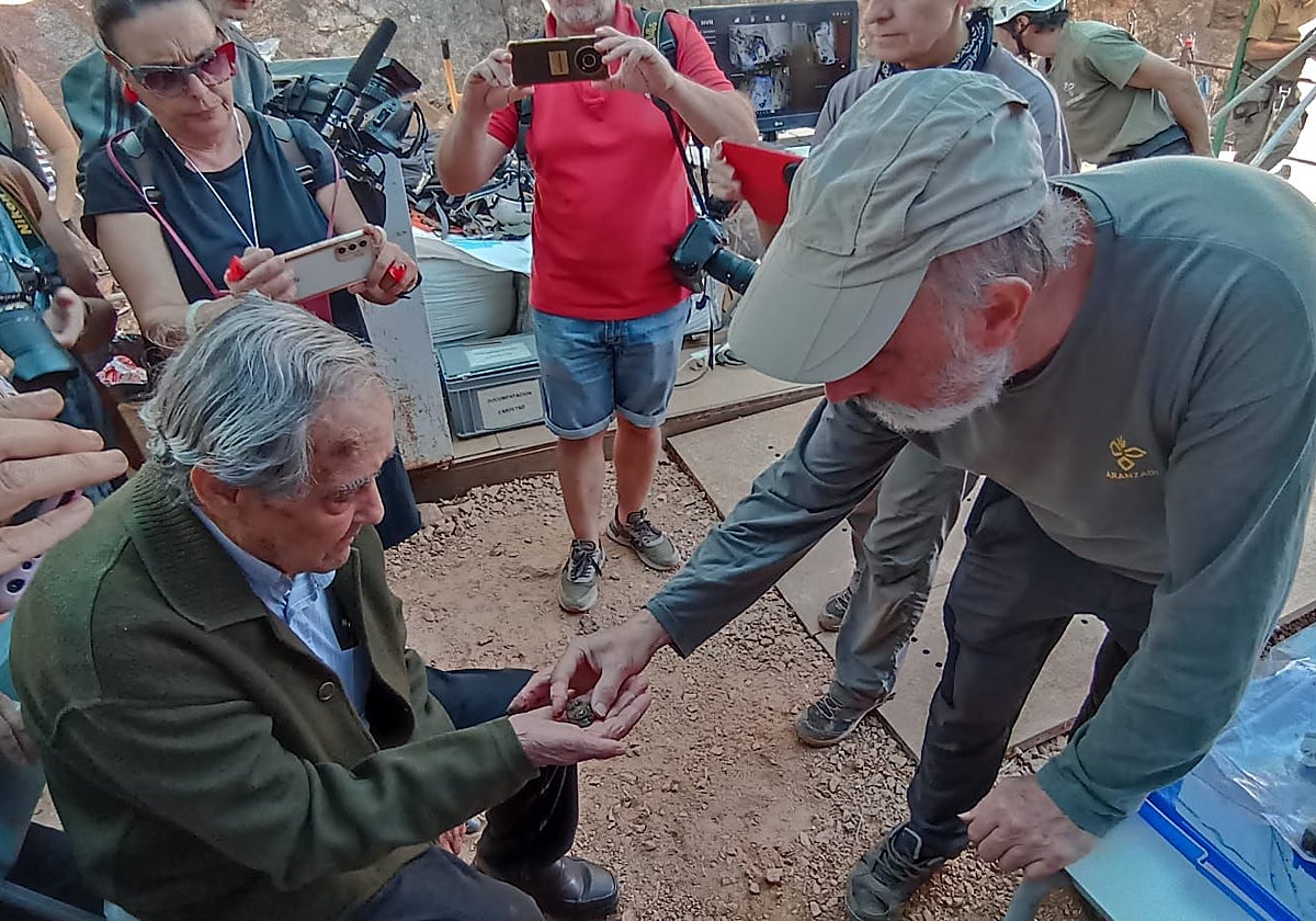 El forense Francisco Etxeberría muestra una moneda a Julio Chaparro, hijo de un represaliado.