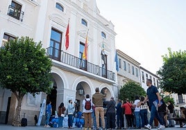 Un grupo de personas delante de la fachada del Ayuntamiento y los periodistas grabando.