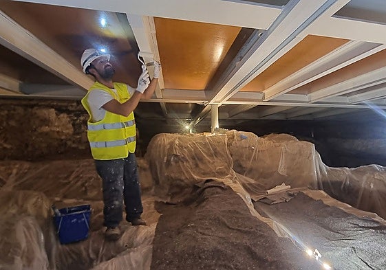 Un trabajador pinta la estructura que separa los restos de la cripta con el altar mayor de la iglesia de Santa Eulalia.