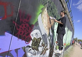 Chino, el escritor que ha creado muchos de los murales que se ven en Badajoz, pinta un 'cocodrilo humanizado' tras firmar en rojo 'HOY Desde 1033', en alusión a este diario