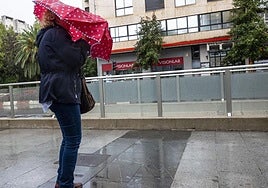 Imagen de archivo de una persona caminando bajo un paraguas un día con mucho viento.