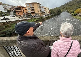 Dos vecinos de Navaconcejo observan la crecida del río Jerte a su paso por la localidad .