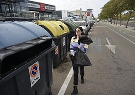 Una pacense lleva una bolsa de basura a un contenedor en la avenida del Diario HOY.