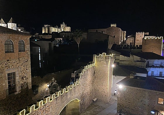 Imagen del Arco de la Estrella, la torre de los Púlpitos y la de la Yerba (al fondo), este miércoles con la iluminación especial de la muralla de Cáceres.