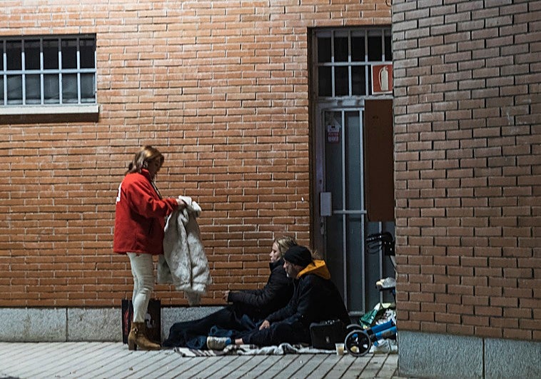 Virginia, voluntaria de Cruz Roja, entrega un abrigo a una pareja que duerme en la estación de autobuses.