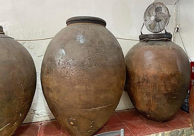 Salón encalado, rodeados de tinajas, con un decorado castizo y ecléctico