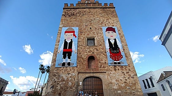 Dos grandes tapices de ganchillo decoran la torre de la iglesia de Aceuchal con dos figuras con el traje típico del pueblo