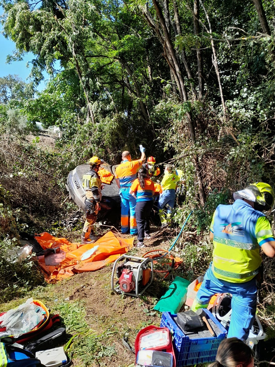Los bomberos trabajan para rescatar a los dos ocupantes del turismo, que se ha salido de la vía y ha caído por un terraplén.