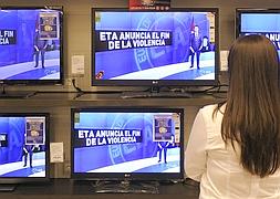 Una ciudadana observa el anuncio del fin de la violencia en la sección de electrodomésticos de un centro comercial. / Foto: Efe | Vídeo: Gara