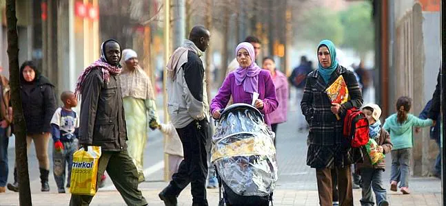 Inmigrantes caminan por una calle de Salt (Gerona). /Archivo