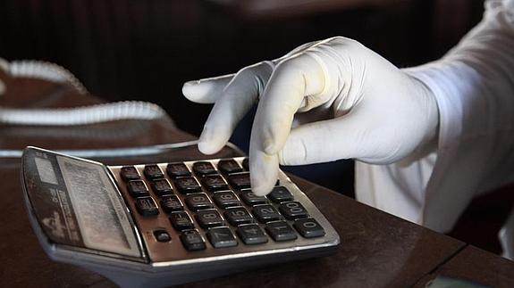 Una dependienta utiliza un guante para usar una calculadora como medida de protección