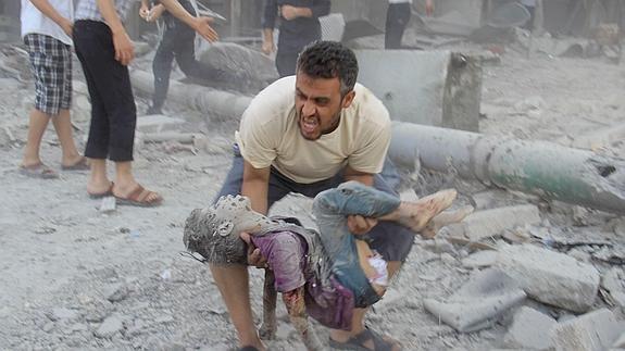 Un sirio recoge el cuerpo de su hijo de los escombros en una calle de Alepo. 
