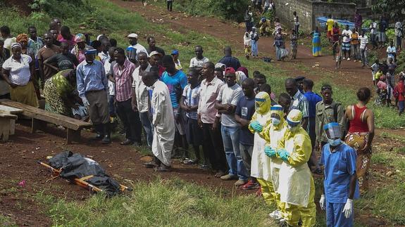 Varias personas rezan ante el cadáver de una víctima de ébola en Freetown, Sierra Leona.