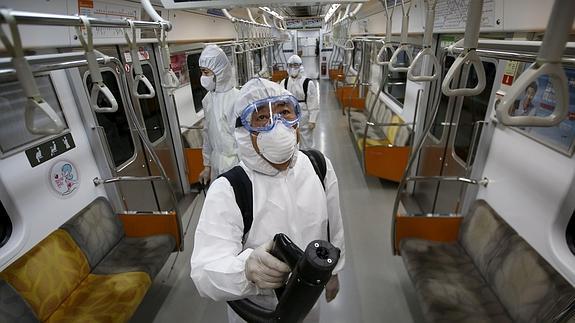 Un equipo de técnicos desinfecta un vagón del metro de Seúl.