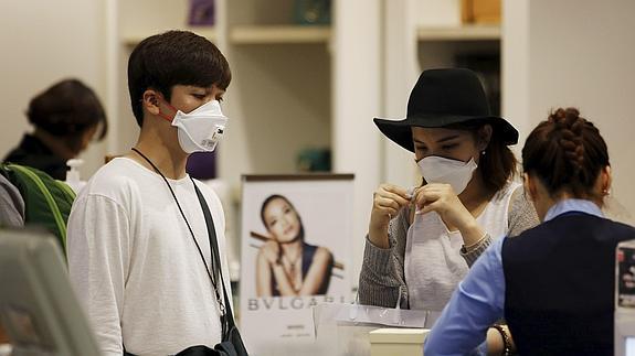 Dos ciudadanos, con mascarillas, durante unas compras en Seúl. 