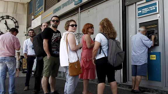 Varios atenienses hacen cola para retirar dinero de un cajero automático.