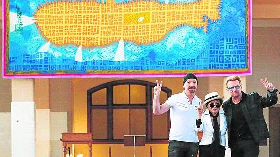 Yoko Ono, viuda de John Lennon, posa con el cantante irlandés Bono y el guitarrista The Edge de U2 durante la inauguración del tapiz en honor al cantante fallecido.
