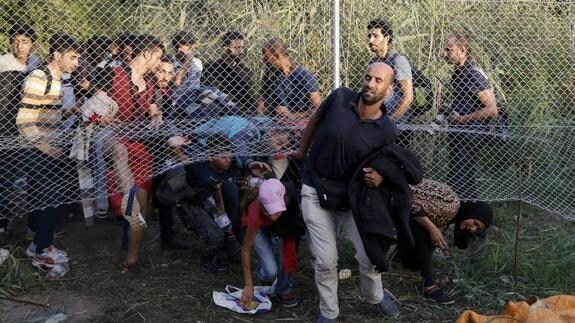 Inmigrantes buscan huecos para cruzar la frontera hasta Hungría.