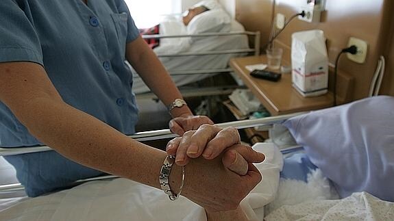 Enfermera conforta a una paciente ingresada en una clínica para ancianos.