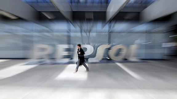 Un hombre camina ante el logo de Repsol en la sede de la compañía en Madrid.