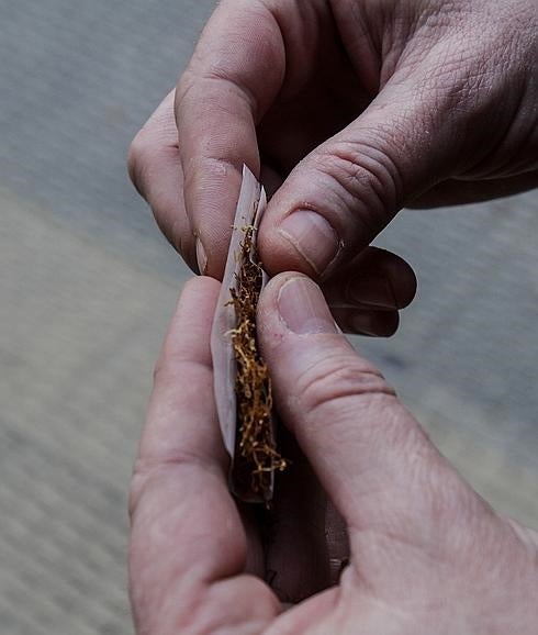 Un joven se lía un porro mezclándolo con tabaco.