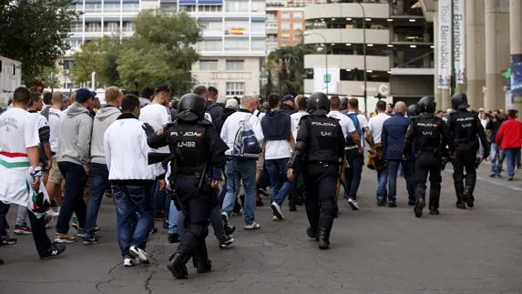 Varios aficionados del Legia caminan escoltados por policías. 